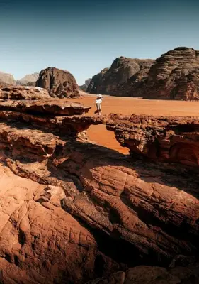 a person standing on a cliff in the desert at Sunrise Magic Camp in Wadi Rum