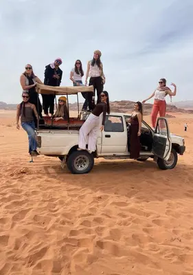 a group of people in the back of a truck in the desert at Sunrise Magic Camp in Wadi Rum