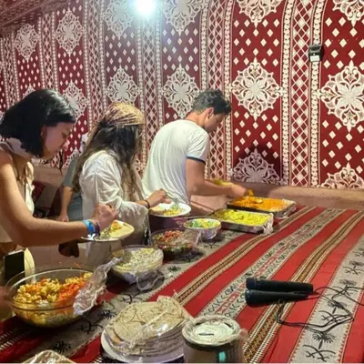 a group of people standing around a table with food at Sunrise Magic Camp in Wadi Rum