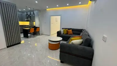 a living room with a couch and a kitchen at Luxury 3 Bedroom Family Apartment in Amman in Amman