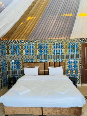 a bedroom with a bed with a blue and white wall at TALA lUXURY CAMP in Wadi Rum
