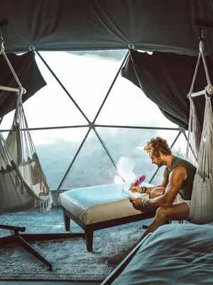 a man sitting on a bed in a tent at Rum marea in Disah