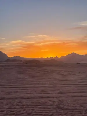 a sunset in the desert with mountains in the background at Starlight Camp in Disah
