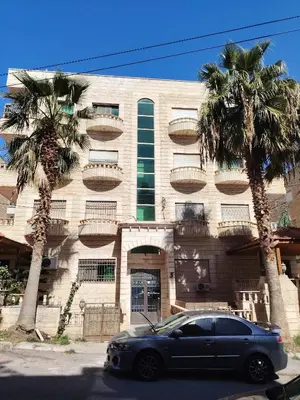 a car parked in front of a building with palm trees at الرائد للشقق المفروشة in Amman