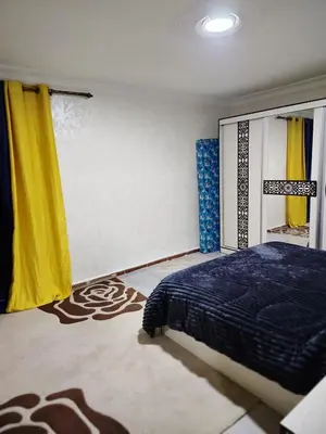 a bedroom with a bed and a yellow curtain at الرائد للشقق المفروشة in Amman