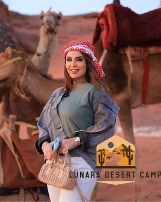 a woman standing in front of a picture of a camel at Lunara Desert Luxury Camp in Wadi Rum