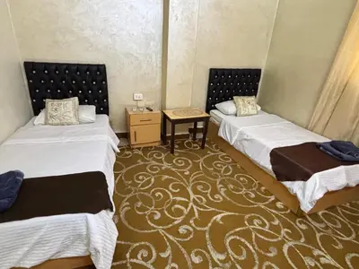 a room with two beds and a table in it at New Hamoudeh Hotel in Amman