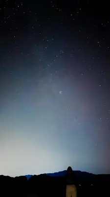 a person standing under a night sky with stars at Wadi Rum Sands Story Camp &Tours in Wadi Rum