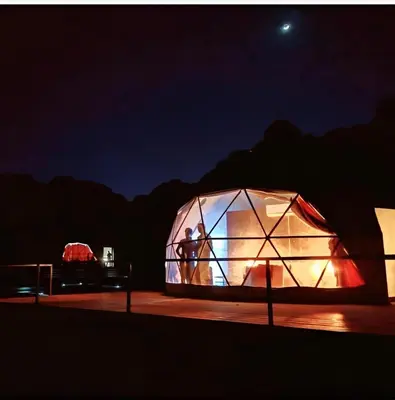 a person standing inside of a greenhouse at night at Wadi rum Hi camp in Wadi Rum