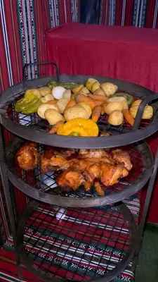 a metal rack with chickens and vegetables on it at Wadi rum Hi camp in Wadi Rum