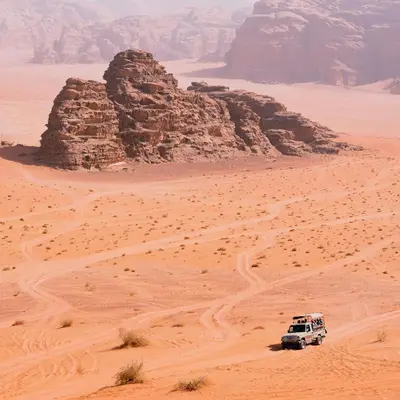 a white truck driving through the desert at Wadi rum Hi camp in Wadi Rum