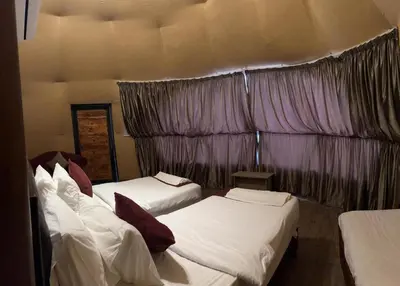 a room with three beds and a curtain at Wadi rum Hi camp in Wadi Rum