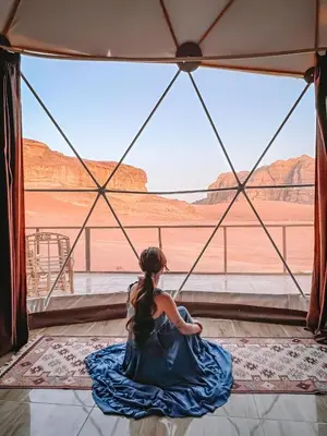 a girl in a blue dress looking out at the desert at Wadi rum tenda camp in Wadi Rum