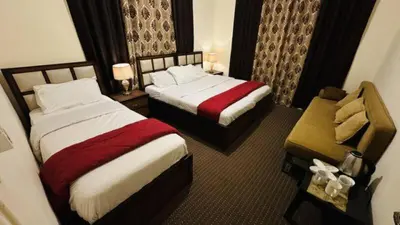 a hotel room with two beds and a bench at Petra center suite in Wadi Musa