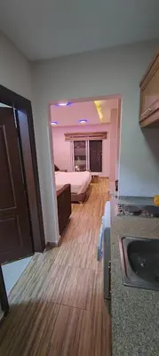 a room with a bed and a kitchen with wooden floors at Fully furnished studio in Amman