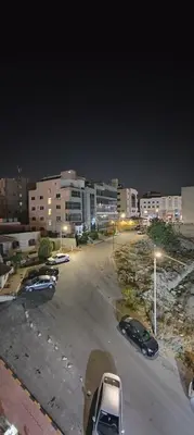 a parking lot with parked cars in a city at night at Fully furnished studio in Amman