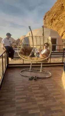 a man sitting in a chair in the desert at Wadi rum naef camp in Wadi Rum