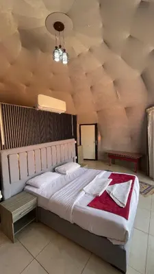a bedroom with a large bed with a red blanket at NOVA lUXURY CAMP in Wadi Rum