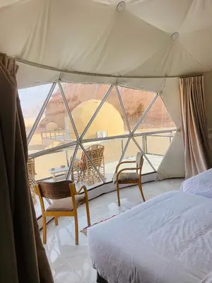 a bedroom with a bed and two chairs in a tent at NOVA lUXURY CAMP in Wadi Rum