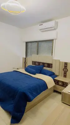 a bedroom with a large bed with blue sheets at شقة مفروشة في طبربور in Amman
