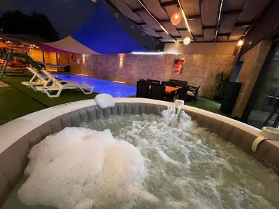 a bath tub filled with water next to a pool at Al Zain Chalet - Private Pool in Al Kafrayn