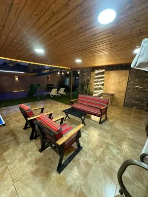 a group of benches sitting in a room with a patio at Al Zain Chalet - Private Pool in Al Kafrayn