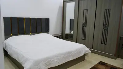 a bedroom with a white bed and a large mirror at Al Zain Chalet - Private Pool in Al Kafrayn
