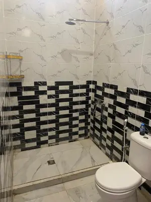 a bathroom with a toilet and a glass shower at هوستل خدمه مبيت in Disah