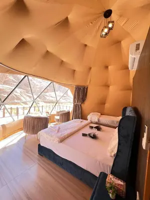 a bedroom with a large bed in a room with a ceiling at Noor Luxury Camp Wadi Rum in Wadi Rum