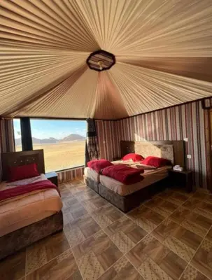 a bedroom with two beds and a large window at Noor Luxury Camp Wadi Rum in Wadi Rum
