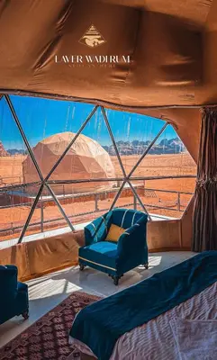 a bed in a tent with a view of the desert at Laver wadi rum in Wadi Rum
