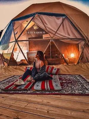 a woman sitting on a rug in a tent at Laver wadi rum in Wadi Rum