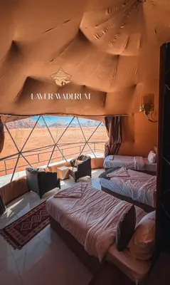two beds in a room with a large window at Laver wadi rum in Wadi Rum