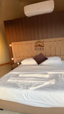 a white bed with a wooden headboard with a sign on it at DARA RUM lUXURY CAMP in Wadi Rum