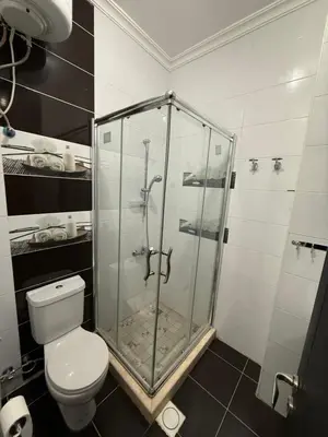 a bathroom with a toilet and a glass shower at Abdallah Wa'el Adham in Aqaba