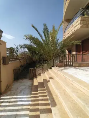 a street in front of a building with palm trees at Abdallah Wa'el Adham in Aqaba