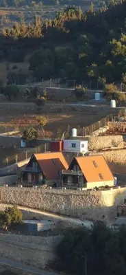 a house with an orange roof in a field at Umm Aljulud Cottages 02 in Ajloun