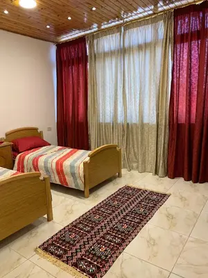 a bedroom with two beds and red curtains and a rug at City View Rooftop Apartment Amman in Amman