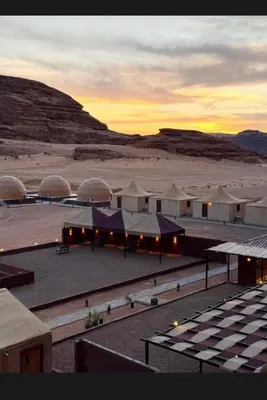 a group of tents in a desert with the sunset at Rum Desert Silence Camp in Wadi Rum