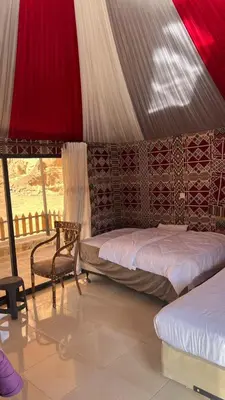 a bedroom with a bed and a chair in a tent at NAJMA lUXURY CAMP in Wadi Rum