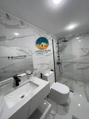 a white bathroom with a toilet and a sink at Giulia Rum Luxury Camp in Wadi Rum