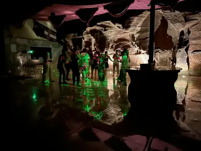 a group of people in a cave with green lights at Fire bedouin camp in Wadi Rum