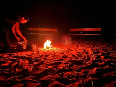 a fire in the middle of a room with two benches at Fire bedouin camp in Wadi Rum