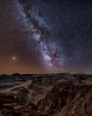 a starry night with the milky way over a mountain at Fire bedouin camp in Wadi Rum