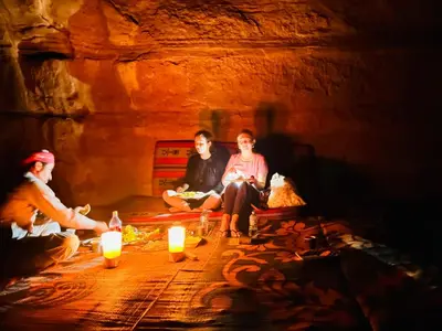 three people sitting around a fire in a cave with candles at Fire bedouin camp in Wadi Rum
