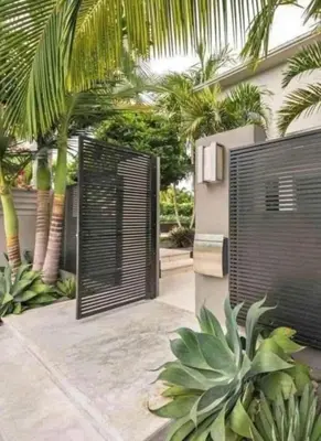 a black gate in front of a house with palm trees at Abu yousef chalet in Irbid