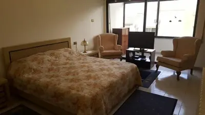 a bedroom with a bed and two chairs and a television at Abdoun rose in Amman