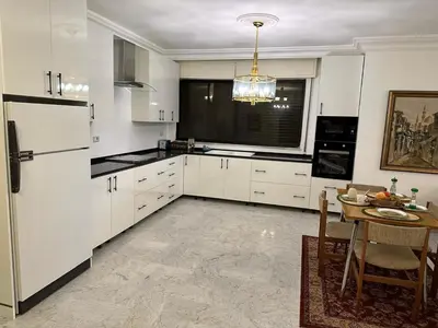 a kitchen with white cabinets and a table in it at Abdoun rose in Amman