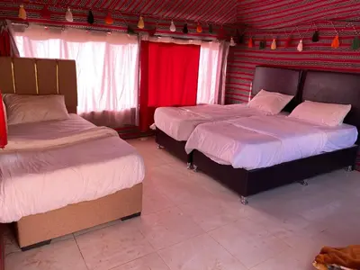 two beds in a room with red curtains at Rum Tale Camp in Wadi Rum