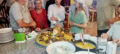 a group of people standing around a table with food at Petra Bed Hostel in Petra